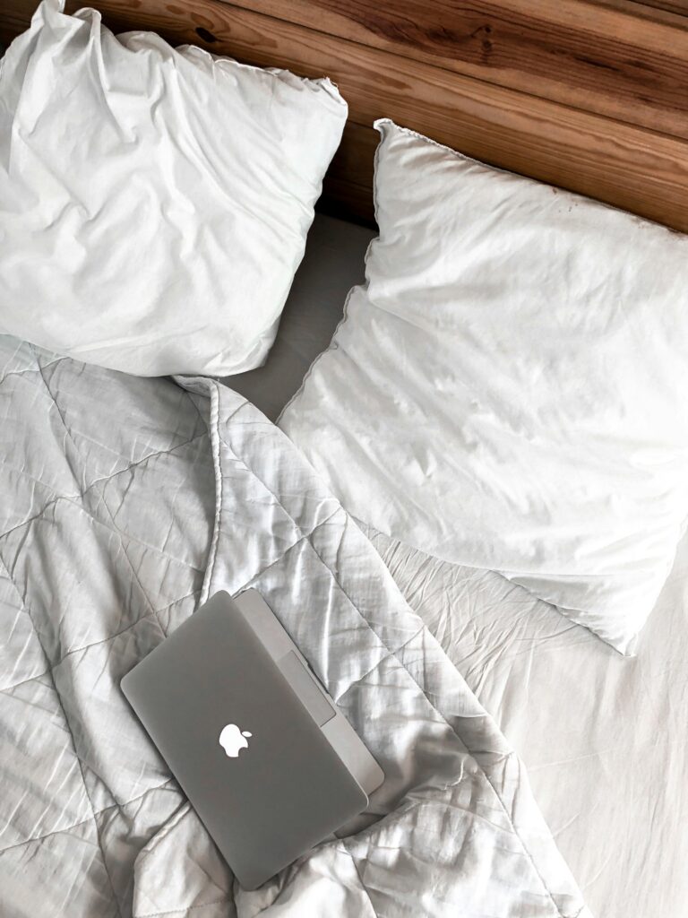 A comfortable bedroom scene with a laptop on a bed, perfect for remote work or relaxation.